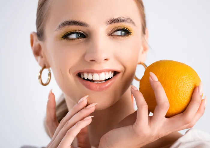 Mulher sorrindo segurando uma laranja